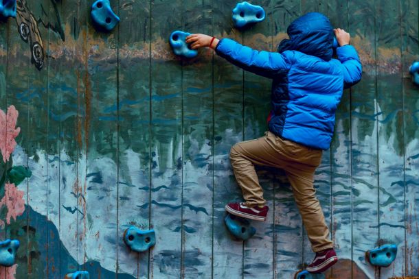 photo of boy wall climbing