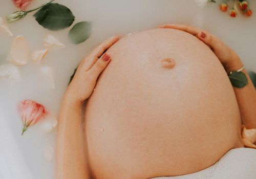 pregnant woman sitting on bathtub