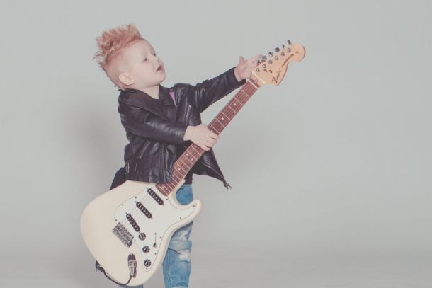 boy wearing black jacket holding electric guitar