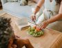 crop pregnant woman cutting fruit for husband