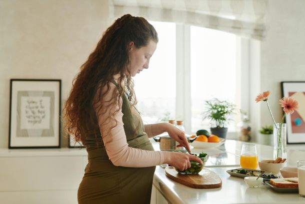 a pregnant woman preparing food on the kitchen counter