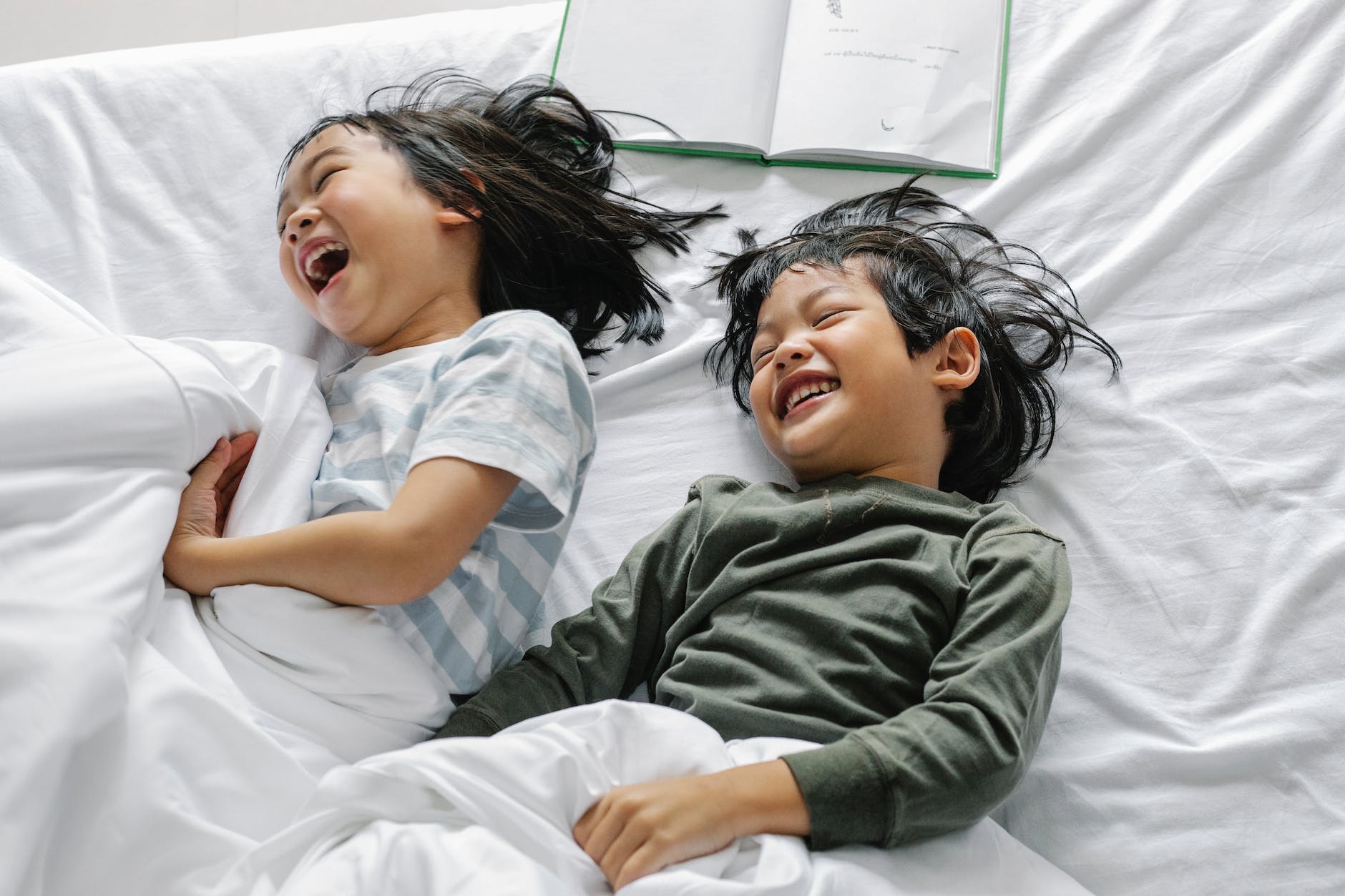 cheerful asian kids having fun in bed